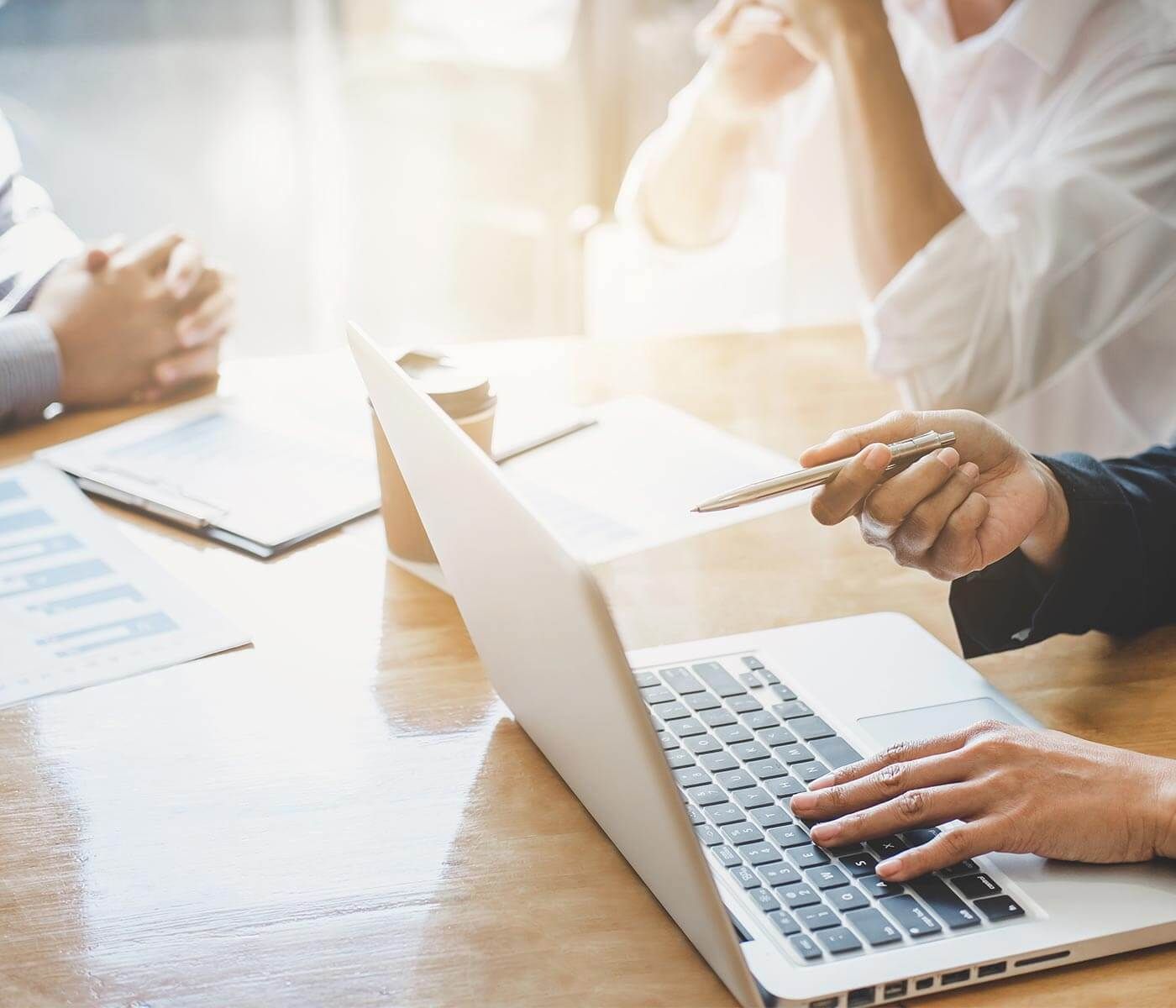 Collaborative Business Meeting with Laptop Close-up of professionals using a laptop during a bright meeting.