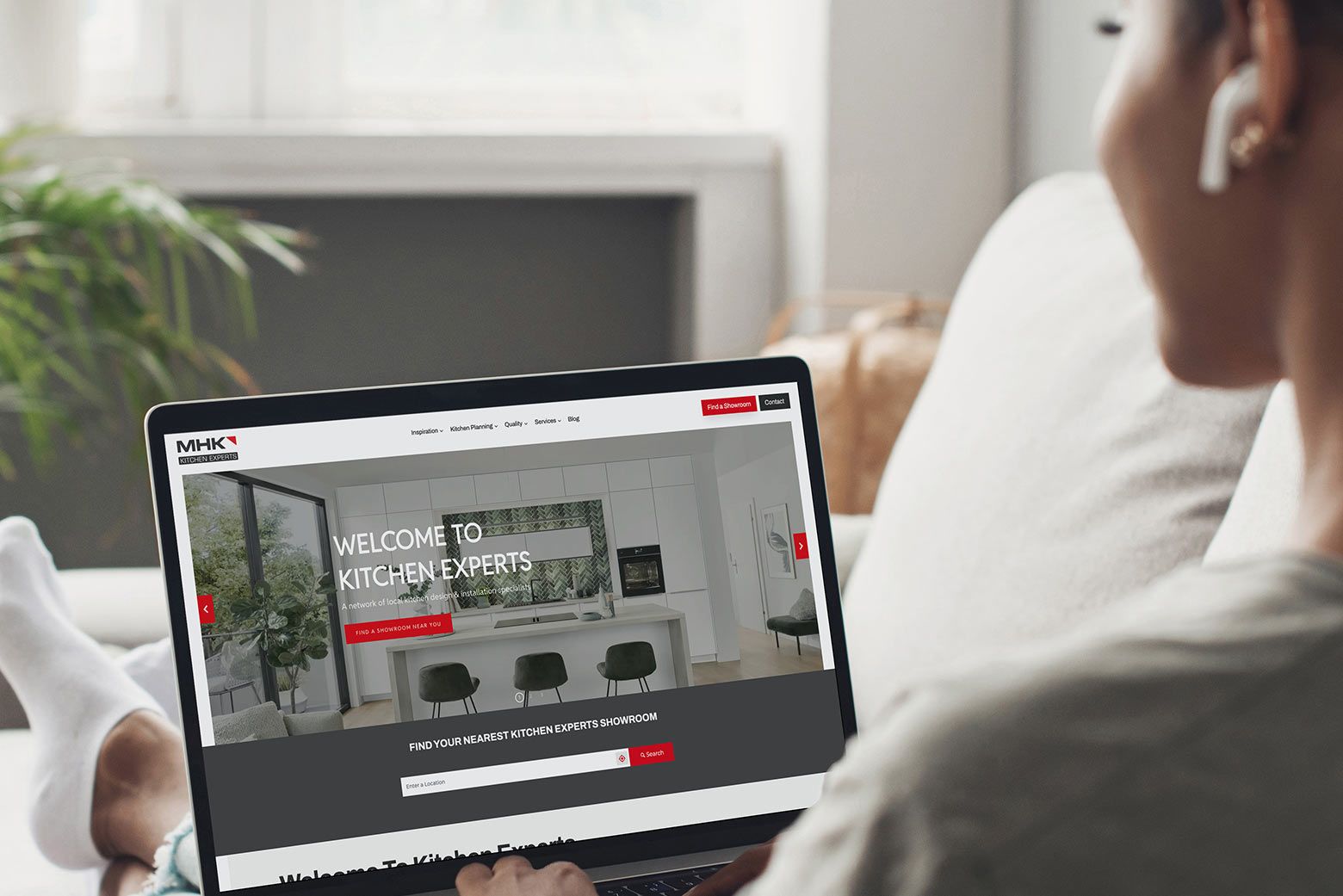 Person Browsing Kitchen Experts Website Over-the-shoulder view of a person using a laptop on a sofa.