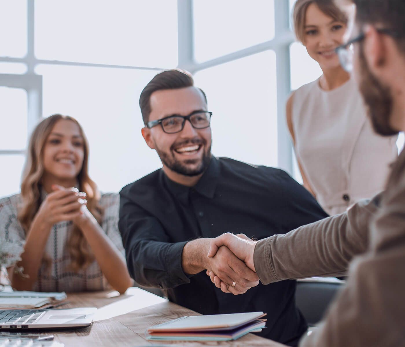 Smiling man in glasses shaking hands during an office meeting.